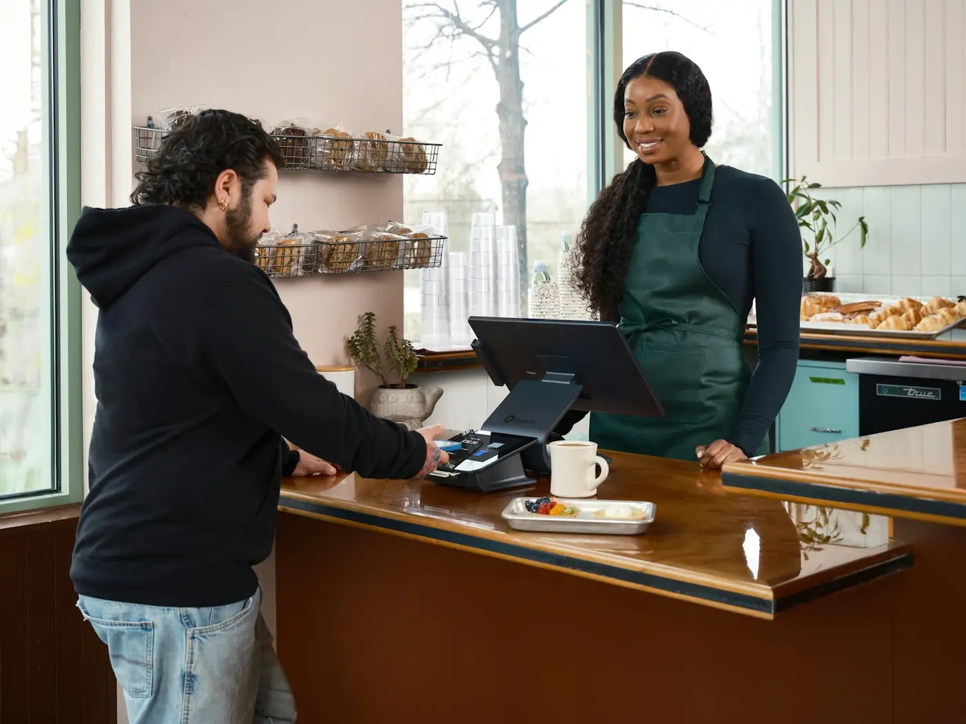A smiling café owner serving a customer at the counter
